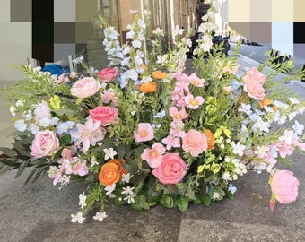 May include: A large floral arrangement with pink, white, and blue flowers. The arrangement is made up of roses, lilies, and other flowers. It is a beautiful and elegant centerpiece.