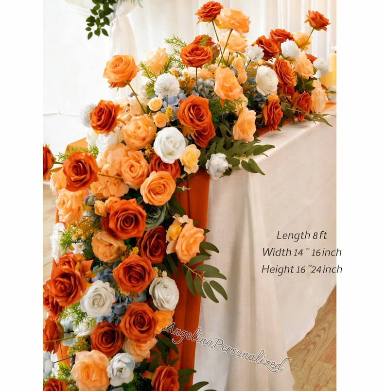 May include: A floral table runner featuring orange, peach, and white roses, with accents of blue and green foliage. The runner is approximately 8 feet long, 14 to 16 inches wide, and 16 to 24 inches high. The text "Angelina Personalized" is visible.