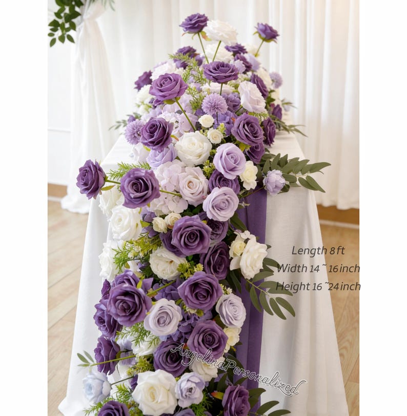 May include: A floral arrangement featuring purple and white roses, lavender hydrangeas, and greenery. The arrangement is displayed on a white tablecloth with a purple runner. The text on the image reads: Length 8 ft, Width 14-16 inch, Height 16-24 inch.