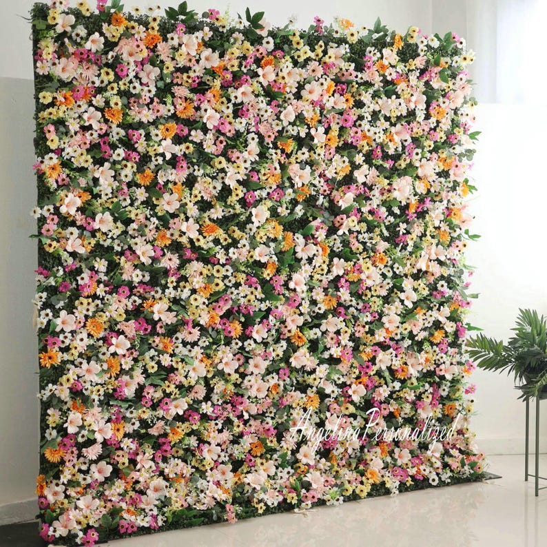 May include: A large floral wall backdrop with a variety of pink, white, and orange flowers. The backdrop is made of artificial flowers and greenery.
