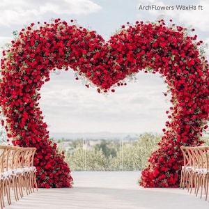 May include: A large heart-shaped floral arch made of red roses, approximately 8 feet wide and 8 feet high, with the text "ArchFlowers W8xH8 ft". The arch is set up for a wedding ceremony, with rows of wooden chairs.