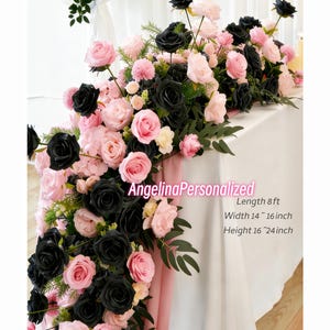 May include: A floral table runner featuring black and pink roses, with greenery accents. The arrangement is approximately 8 feet long, 14 to 16 inches wide, and 16 to 24 inches high. The text "AngelinaPersonalized" is visible.