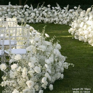 May include: White flower arrangements for a wedding ceremony. The arrangements are made of white baby's breath and white roses. They are arranged in a long line down the aisle, with clear chairs in the foreground. Length 2ft * 20pcs, Width 13-18inch, Height 14-24inch.
