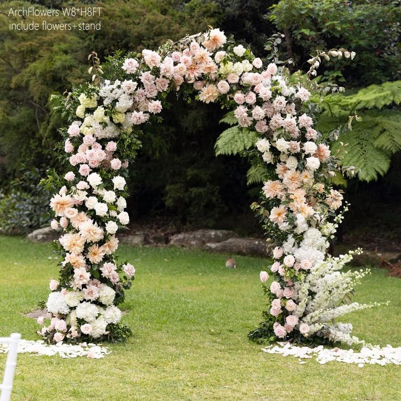 K&ouml;nnte beinhalten: Ein dekorativer Blumenbogen, ca. 244 cm breit und 244 cm hoch, mit wei&szlig;en, pfirsichfarbenen und rosa Bl&uuml;ten. Der Bogen steht auf einer gr&uuml;nen Wiese, mit dem Text "ArchFlowers W8*H8FT include flowers + stand".