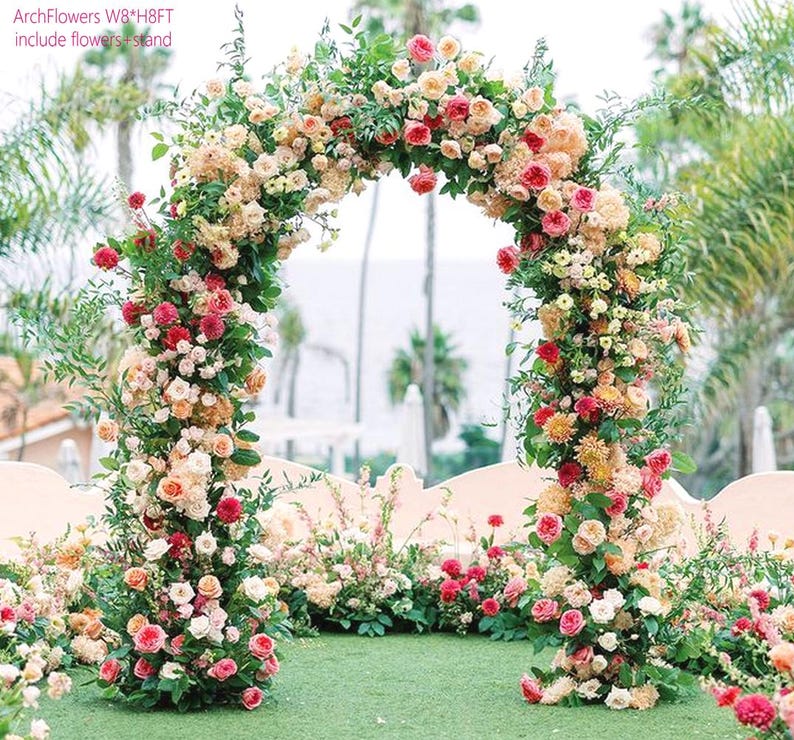 K&ouml;nnte beinhalten: Ein dekorativer Blumenbogen, geschm&uuml;ckt mit einer Vielzahl von Rosen in Rot-, Rosa- und Cremet&ouml;nen, bildet einen auff&auml;lligen Mittelpunkt. Der Bogen ist etwa 2,4 Meter hoch und 2,4 Meter breit, ideal f&uuml;r Veranstaltungen im Freien. Gr&uuml;nes Laub erg&auml;nzt die bunten Bl&uuml;ten.