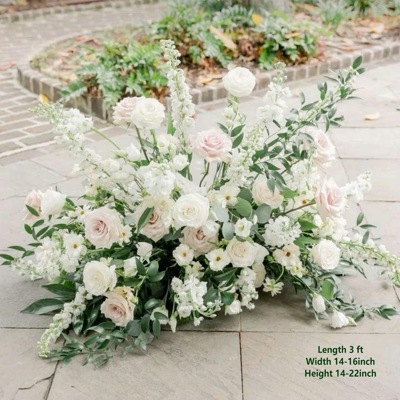 May include: A floral arrangement featuring white and pale pink roses, white delphinium, and green foliage. The arrangement has a length of 3 ft, a width of 14-16 inches, and a height of 14-22 inches, as indicated by the text on the image.