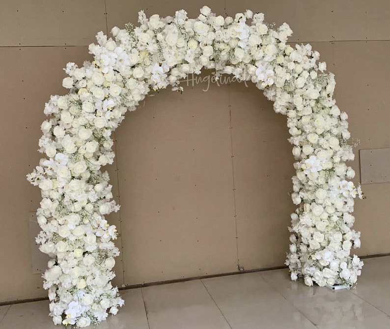 May include: A white floral archway made of white roses, orchids, and baby's breath. The archway is perfect for a wedding ceremony or other special event.