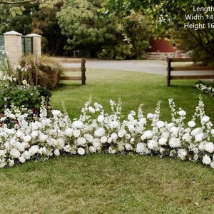 Op de afbeelding: Een witte bloemenboog gemaakt van witte bloemen en groen. De boog is 12 voet lang, 14-16 inch breed en 16-24 inch hoog.