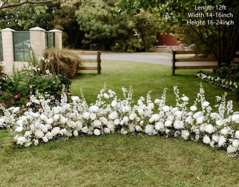 Op de afbeelding: Een witte bloemenboog gemaakt van witte bloemen en groen. De boog is 12 voet lang, 14-16 inch breed en 16-24 inch hoog.