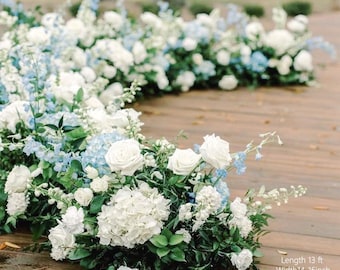 Puede incluir: Arreglo floral con rosas blancas, hortensias y delfinios azules, con follaje verde, sobre una superficie de madera. El texto de la imagen dice: Longitud 13 ft, Ancho 35-41 cm, Altura 35-56 cm.