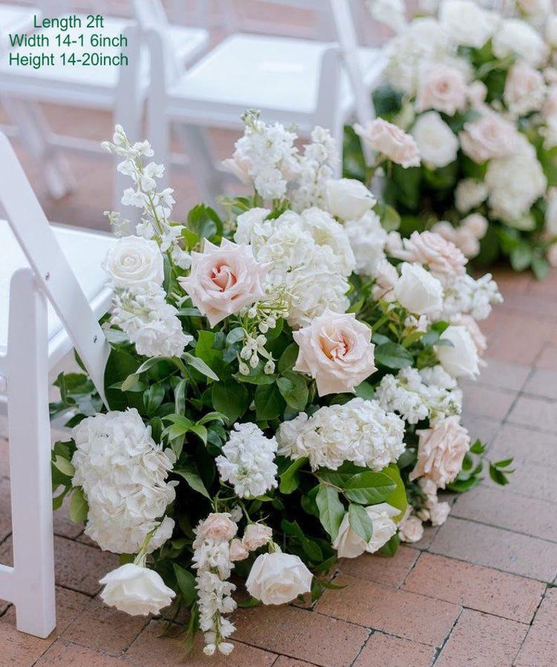 Puede incluir: Un pasillo de ceremonia de boda decorado con un gran arreglo de flores blancas y rosa p&aacute;lido. Las flores incluyen rosas, hortensias y otras flores. El arreglo mide aproximadamente 60 cm de largo, 35-40 cm de ancho y 35-50 cm de alto.