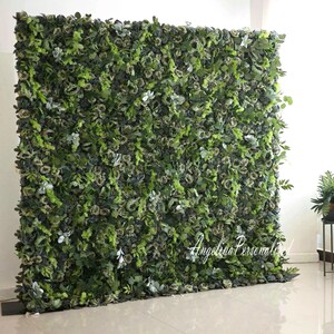 May include: A green artificial flower wall backdrop with a variety of green leaves and flowers. The wall is made of individual pieces that can be arranged to create a custom design. The wall is perfect for weddings, parties, and other events.