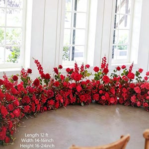 May include: A large, curved floral arrangement featuring numerous vibrant red roses and tall red snapdragon stalks with green foliage. The text on the image indicates a length of 12 ft, a width of 14-16 inches, and a height of 16-24 inches.