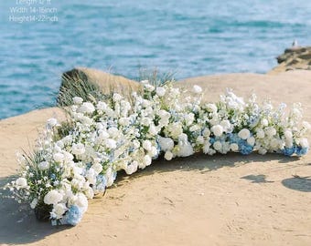 Puede incluir: Arreglo floral con flores blancas y azules, de aproximadamente 3,66 m de largo, 35,56-40,64 cm de ancho y 35,56-55,88 cm de alto. El arreglo está sobre una superficie arenosa con el mar al fondo.