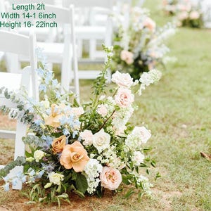 Puede incluir: Un pasillo de boda decorado con sillas blancas y arreglos florales. Los arreglos est&aacute;n hechos con flores blancas, melocot&oacute;n y azules. Las flores est&aacute;n dispuestas en cascada y tienen aproximadamente 60 cm de largo, 35-40 cm de ancho y 40-55 cm de alto.
