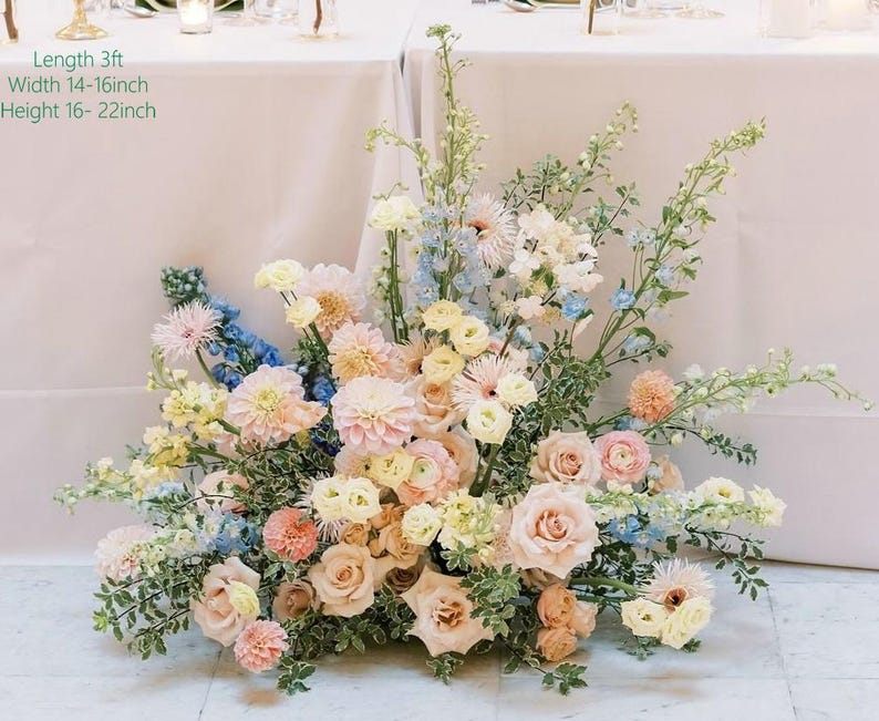 May include: A large floral arrangement in pastel shades, including roses and dahlias. The arrangement is approximately 91cm long, 36-41cm wide, and 41-56cm high. The image text reads: Length 3ft, Width 14-16inch, Height 16-22inch.