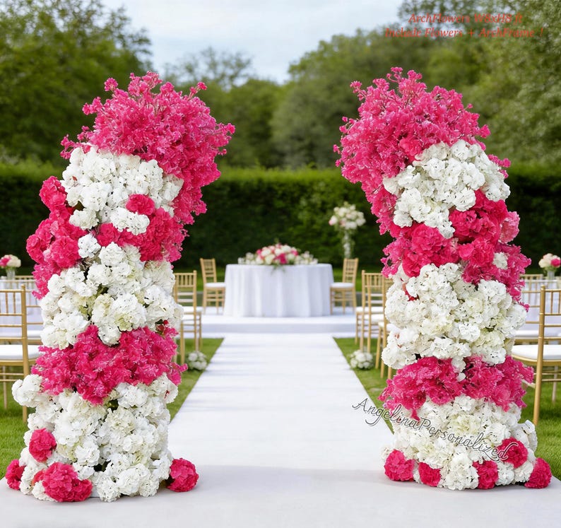 May include: Two floral arches, composed of white and hot pink flowers, frame a wedding aisle. The arches are made of a mix of white and pink flowers, with a dense arrangement. A white carpet leads to a table with a floral centerpiece.
