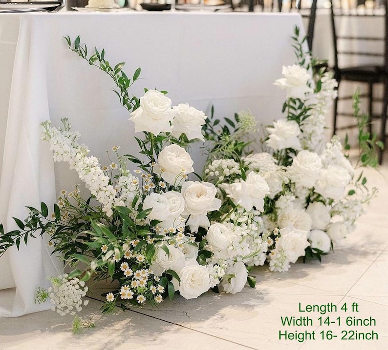 Puede incluir: Arreglo floral blanco con vegetaci&oacute;n, con rosas, hortensias y otras flores blancas. El arreglo mide 1,22 metros de largo, 35-40 cent&iacute;metros de ancho y 40-55 cent&iacute;metros de alto.