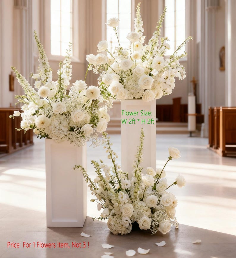 May include: Three white floral arrangements, each with a variety of white flowers, including roses and hydrangeas. The arrangements are displayed on white pedestals. The text on the image says "Flower Size: W 2ft * H 2ft".