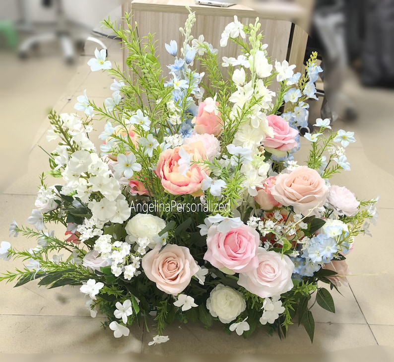 May include: A floral display with pink, white, and blue flowers, including roses and peonies, and green foliage. The arrangement is a mix of different blooms. The text "AngelinaPersonalized" is visible.