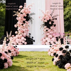 May include: Floral arrangement with pink and black flowers, used for wedding decor. The arrangement is set against a backdrop of black, white, and pink fabric. The height is 16-24 inches, and the width is 14-16 inches.