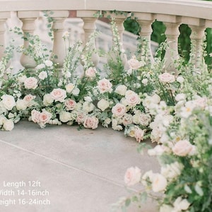 Op de afbeelding: Een bruiloftceremonie achtergrond gemaakt van witte en roze bloemen, groen en wijnstokken. De bloemstukken zijn 3,66 meter lang, 35,56 tot 40,64 centimeter breed en 40,64 tot 61 centimeter hoog.