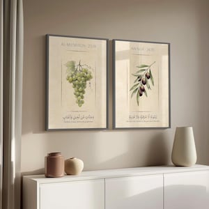 May include: Two framed botanical prints. One features a cluster of green grapes with Arabic text and the words "Gardens of date palms and grapevines." The other print shows an olive branch with olives and Arabic text that reads "An olive tree, neither of the east nor of the west."