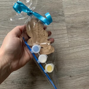 Pu&ograve; includere: Un sacchetto di cellophane trasparente legato con un nastro blu contiene una figura di legno dei Puffi, vasetti di vernice e un pennello. Il Puffo &egrave; non verniciato e pronto per essere colorato. I vasetti di vernice sono blu, bianchi e gialli.