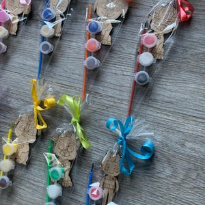 Pu&ograve; includere: Un set di sei figure di legno da dipingere, ciascuna confezionata con un piccolo pennello e tre piccoli barattoli di vernice. Le figure sono avvolte in plastica trasparente e legate con nastri colorati.