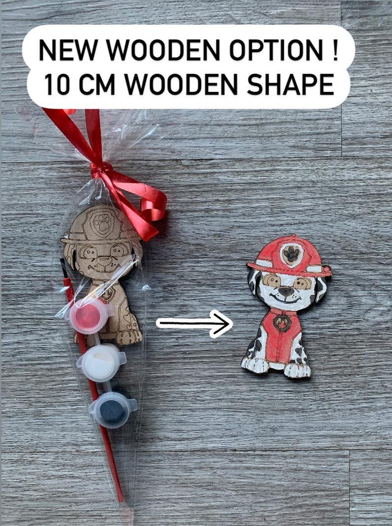 Pu&ograve; includere: Un kit di pittura in legno per dipingere il tuo personaggio con un cane dei cartoni animati che indossa un cappello da pompiere rosso. Il kit include tre piccoli barattoli di vernice, un pennello e una forma in legno di 10 cm. "NEW WOODEN OPTION! 10 CM WOODEN SHAPE" &egrave; scritto sulla confezione.