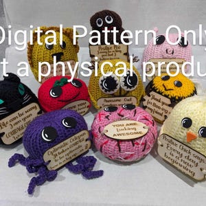 May include: A collection of 10 crocheted amigurumi toys with different designs and colors. Each toy has a small wooden sign attached with a positive message. The signs include messages like "Life can be scary, I am your courage cushion", "Positive Poo", "Awesome Owl", "You are freaking awesome", "Thank you for bee-ing my friend", "Optimistic Octopus", "Love you", and "Positive Chick says: Every day is a new beginning".