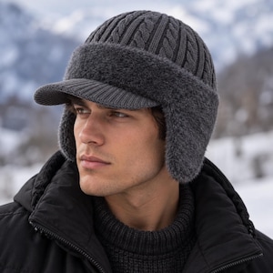 May include: A dark gray knit cap featuring a cable knit pattern on the crown, a stiff brim, and plush, fuzzy ear flaps. The hat is constructed with a ribbed texture on the brim and a soft, fleece-like material lining the ear flaps and front band.