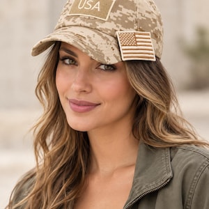 May include: A tan and brown digital camouflage baseball cap featuring a rectangular patch with the text USA on the front crown and a small embroidered American flag patch attached to the left side of the brim, constructed with a structured front panel.