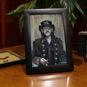 May include: A framed painting of a man wearing a black hat and sunglasses. He is wearing a dark jacket with gold buttons and a white shirt. The background is a blue and green watercolor wash.