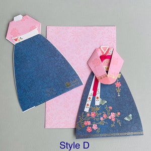 May include: A blue and pink paper craft card featuring a traditional Korean dress, or Hanbok, with floral details. The card is labeled "Style D".