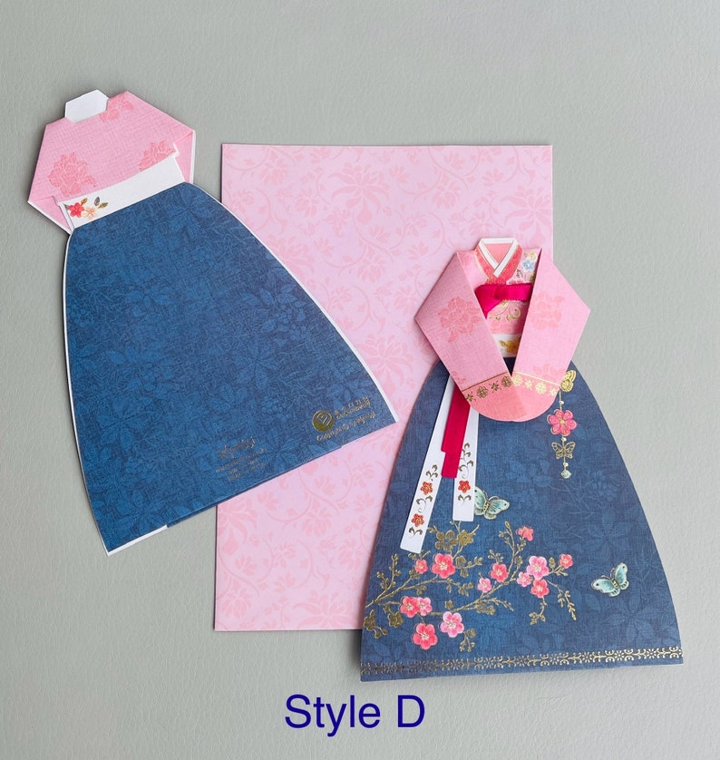 May include: A blue and pink paper craft card featuring a traditional Korean dress, or Hanbok, with floral details. The card is labeled "Style D".