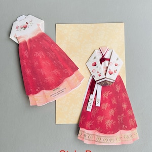 May include: Two red and white paper cut-out dresses in the style of traditional Korean Hanbok. The dresses are decorated with floral patterns and gold accents. The text "Style B" is printed below the dresses.
