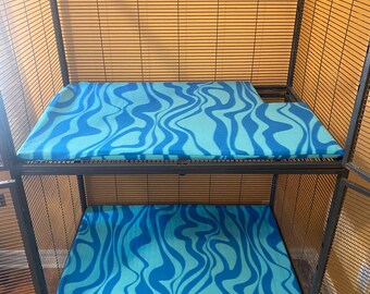 May include: A black metal cage with two levels. Each level has a blue and turquoise patterned fleece liner.