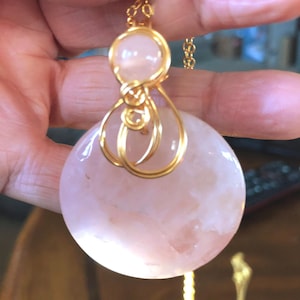 Rose quartz round w/bead, wrapped in gold toned tarnish resistant wire. Wear this beautiful pendant by your heart chakra to Bring the love!