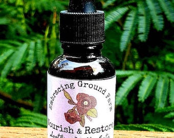 May include: A brown glass bottle with a dropper top and a white label that reads "Embracing Ground Farm Nourish & Restore Soothing Milky Oats Elixir for exhaustion - healthier stress response organic/gluten-free ingredients avena sativa/milky oats + alcohol 1 fl oz"