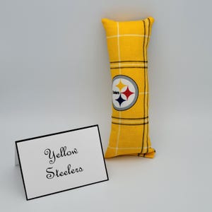 May include: Yellow and black Pittsburgh Steelers pillow with a plaid pattern. The pillow has the Steelers logo on it and the text "Yellow Steelers" on a white card.