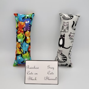May include: Two cat-shaped toys. One is black with a rainbow pattern of cats and the other is grey flannel with black and white cats. The text on the card reads "Rainbow Cats on Black" and "Grey Cats (Flannel)"