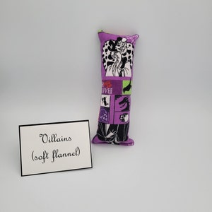 May include: Purple and green fabric pillow with a black and white illustration of Cruella De Vil from Disney's 101 Dalmatians. The pillow is labeled "Villains (soft flannel)".