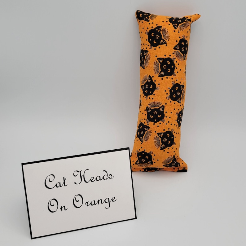 May include: Orange cat head print fabric pillow with the text "Cat Heads On Orange" on a white card.