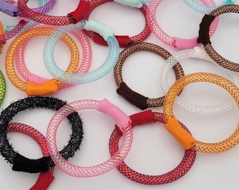 May include: Assortment of colorful, iridescent, and textured hair ties. The hair ties are made of a variety of materials, including fabric, elastic, and metal. They are all in a variety of colors, including pink, blue, orange, red, and black.