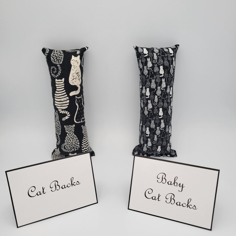 May include: Two black and white cat-print fabric catnip toys. The toy on the left says "Cat Backs" and the toy on the right says "Baby Cat Backs".