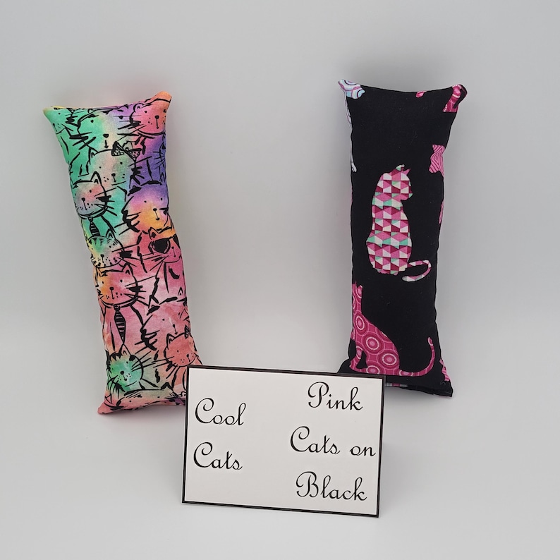 May include: Two cat-themed catnip toys. One toy is a rainbow fabric with black cat silhouettes. The other toy is black fabric with pink cat silhouettes. The text on the card reads "Cool Cats" and "Pink Cats on Black".