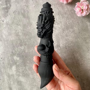May include: A black dragon-shaped brush with a detailed design. The brush is made of a smooth, rubbery material and has a long, thin handle.