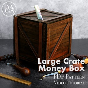 Puede incluir: Una caja de dinero de cuero marrón con forma de caja grande con una ranura para billetes. La caja está decorada con costuras y tiene un aspecto rústico. El texto "Large Crate Money Box" está impreso debajo de la caja. El texto "PDF PATTERN VIDEO TUTORIAL" está impreso debajo del texto.