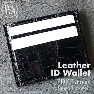 May include: A black leather ID wallet with two card slots. The wallet has a crocodile embossed pattern and the text "Leather ID Wallet PDF Pattern Video Tutorial" is printed on the bottom.